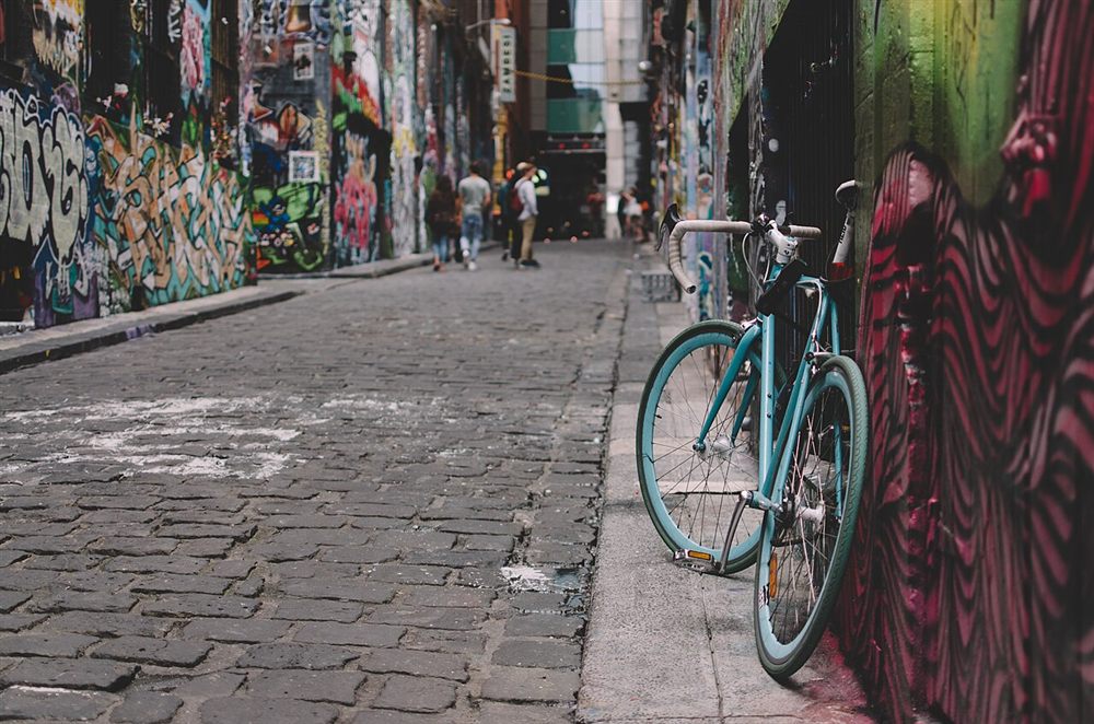 A bicycle leaning against painted walls on the cobbled Hosier Lane