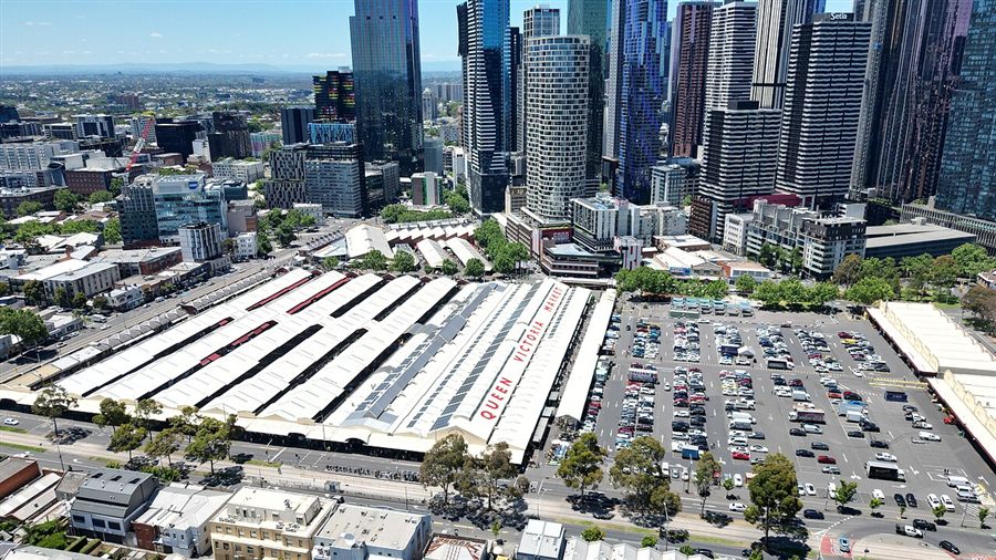The long rooftops of Queen Victoria Market's open-air sheds with city towers behind
