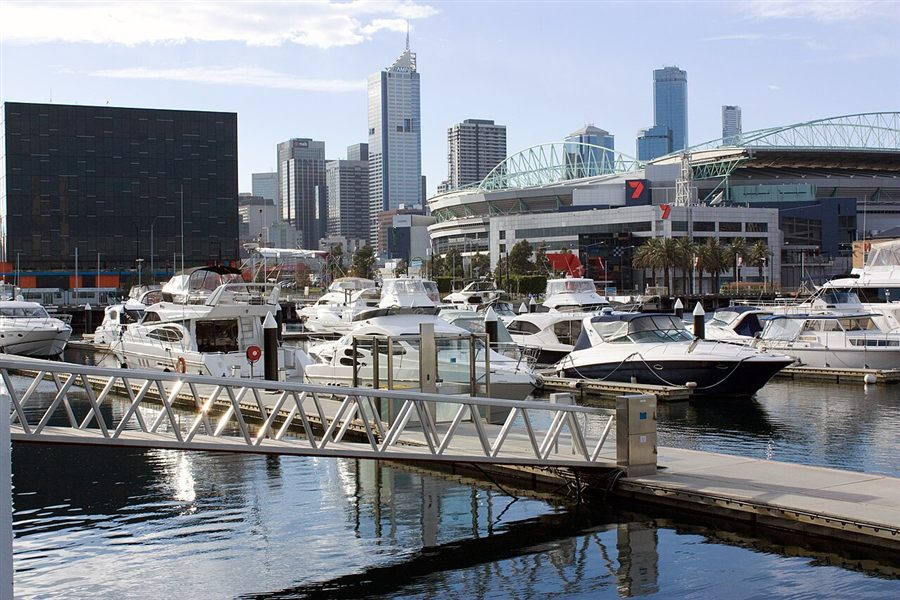 Motor yachts moored at a Docklands marina with the stadium and city behind