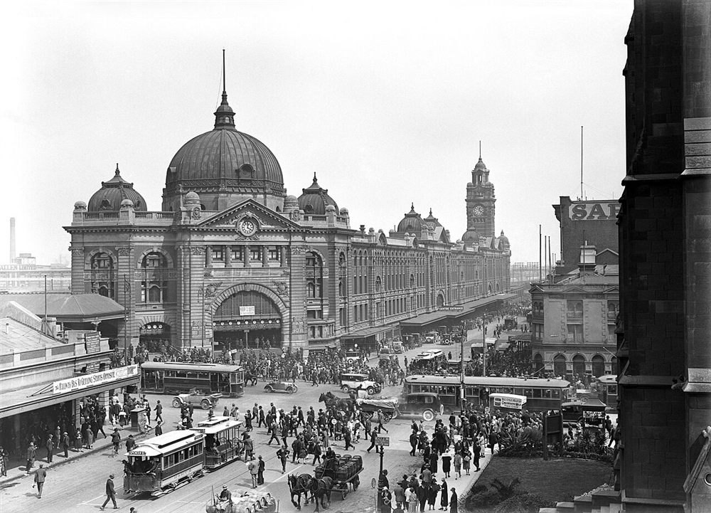 Black and white photo of trams, carts and crowds outside Flinders Street Station in 1927