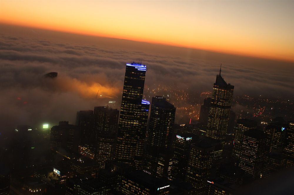 Thick fog covering the city with towers rising above it at dusk