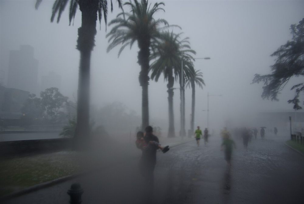 People running through a hailstorm under palm trees by the river